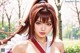 woman with long brown hair in a ponytail, wearing a white and red outfit, standing in a cherry blossom garden.