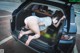 A woman wearing a face mask is sitting in the back of a car.