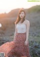 A woman in a white top and a long skirt posing for a picture.