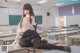 A woman sitting on a desk in a classroom.