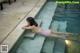 A woman in a pink bikini laying on the edge of a swimming pool.
